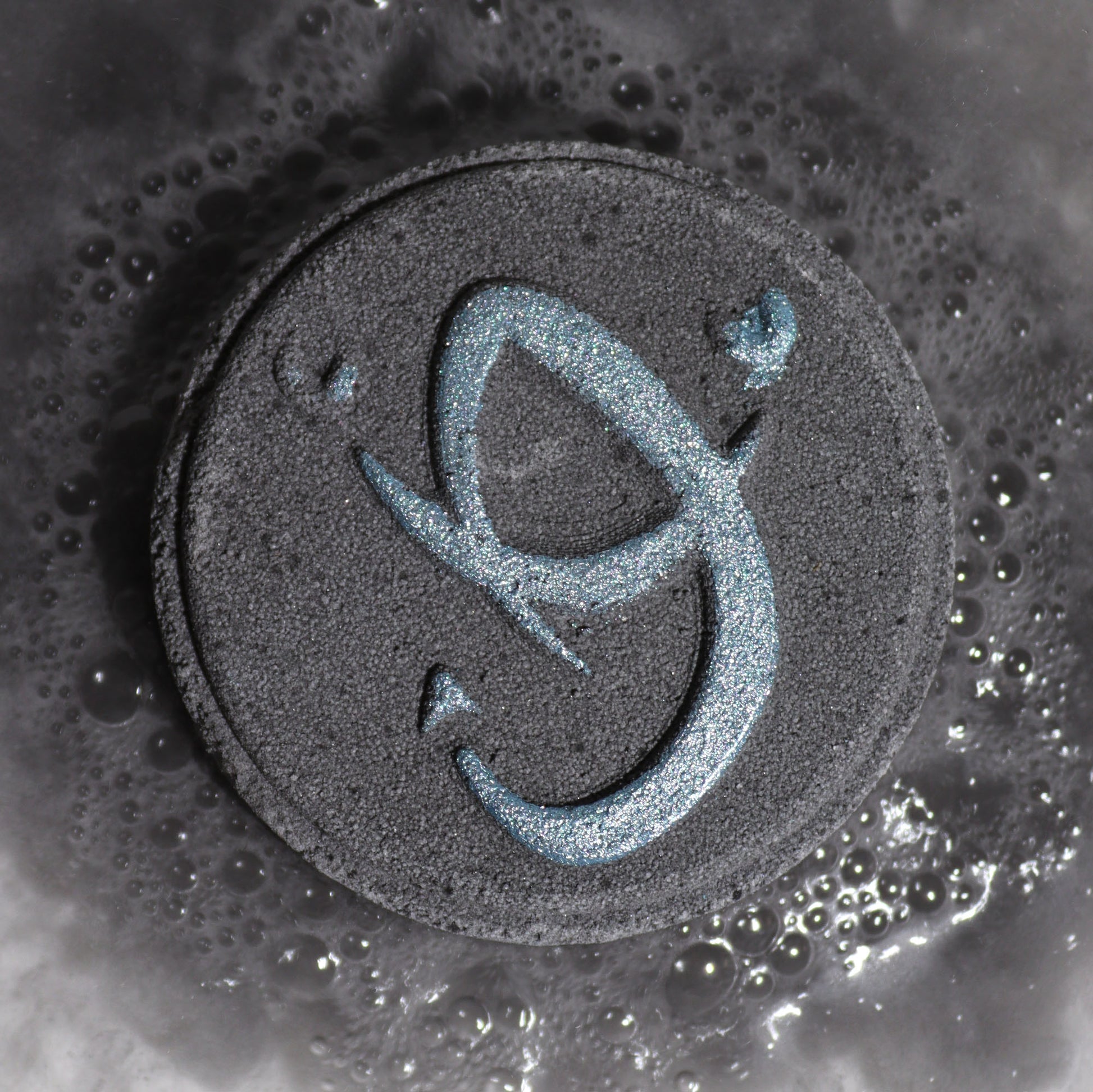 Close-up of Scorpio bath bomb fizzing in water with rich, dark colours and mysterious spicy fragrance